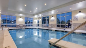An indoor swimming pool with clear water, a lifeguard station, and a pool lift.
