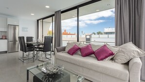 Ein modernes Wohnzimmer mit einer Couch, einem Glastisch und einem Essbereich mit Stühlen und einem Tisch.
