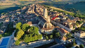 An aerial view of a town with a prominent church, a river, and surrounding fields. - Gîte de la cathédrale in downtown Lectoure (Lectoure)