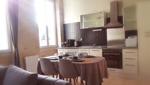 A modern kitchen with a dining area, featuring a large window, a built-in stove, and a microwave. - Gîte de la cathédrale in downtown Lectoure (Lectoure)