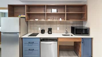 Cocina compacta equipada con refrigerador, lavavajillas, microondas y cafetera.