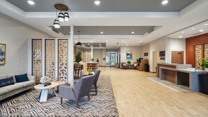 A spacious living area with a sofa, chairs, a coffee table, and a reception desk. - Candlewood Suites Asheville Downtown by IHG (Asheville)