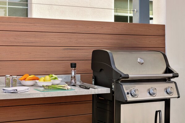 Una parrilla exterior con acabado de acero inoxidable, un quemador a gas y un panel de control con tres perillas.