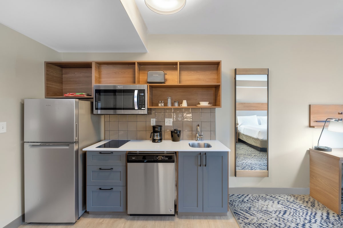 Una cocina compacta equipada con refrigerador, microondas, cafetera y lavavajillas.