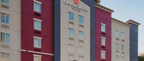 Een hotel met een moderne gevel, een overdekte ingang en een heldere lucht.