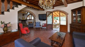 Amplia sala de estar con techo de madera, una araña, televisor y comedor con mesa y sillas.