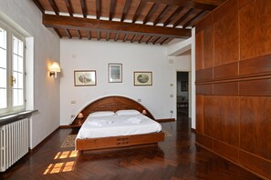 Quarto com cama de madeira, radiador e luminárias fixadas na parede.