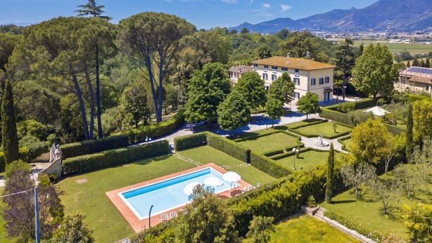 Una extensa propiedad con piscina, jardines cuidados y vistas a montañas distantes.