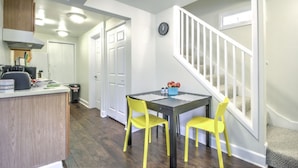 A kitchen with a dining area, a clock on the wall, and a staircase.