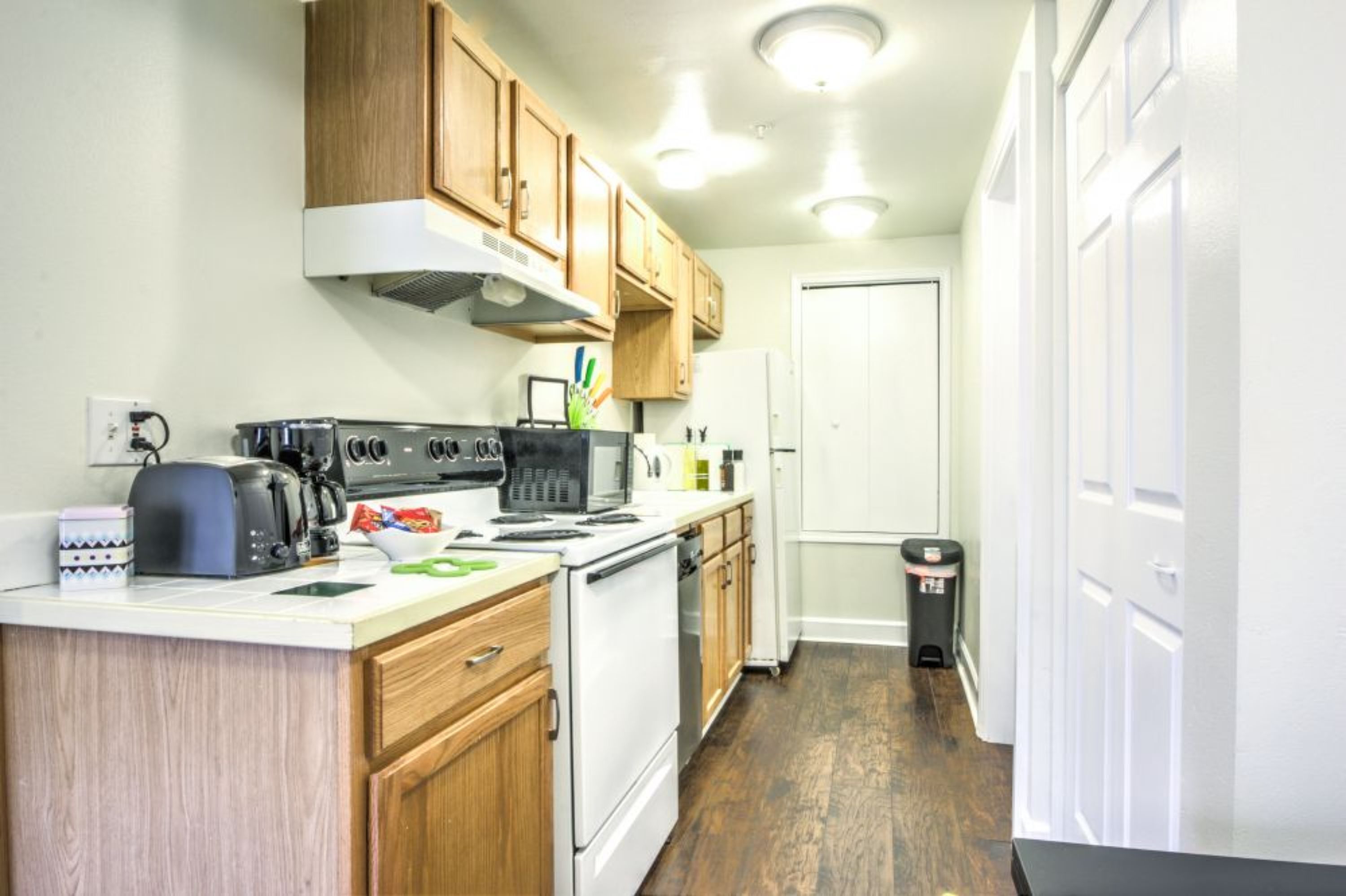 A compact kitchen with wooden cabinets, a stove, and a refrigerator.