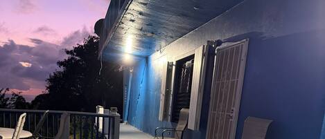 Un espace extérieur abrité, avec un mur bleu, deux chaises, une table et une plante en pot.
