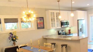 Una cocina moderna con armarios blancos, microondas integrado y refrigerador de acero inoxidable.