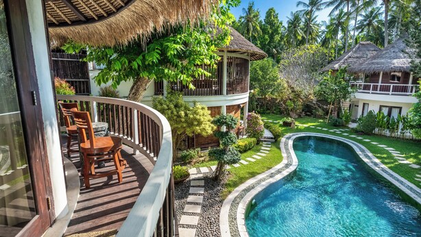 A resort with a pool, wooden deck, and thatched-roof structures. - The Village of Angels (Manggis)