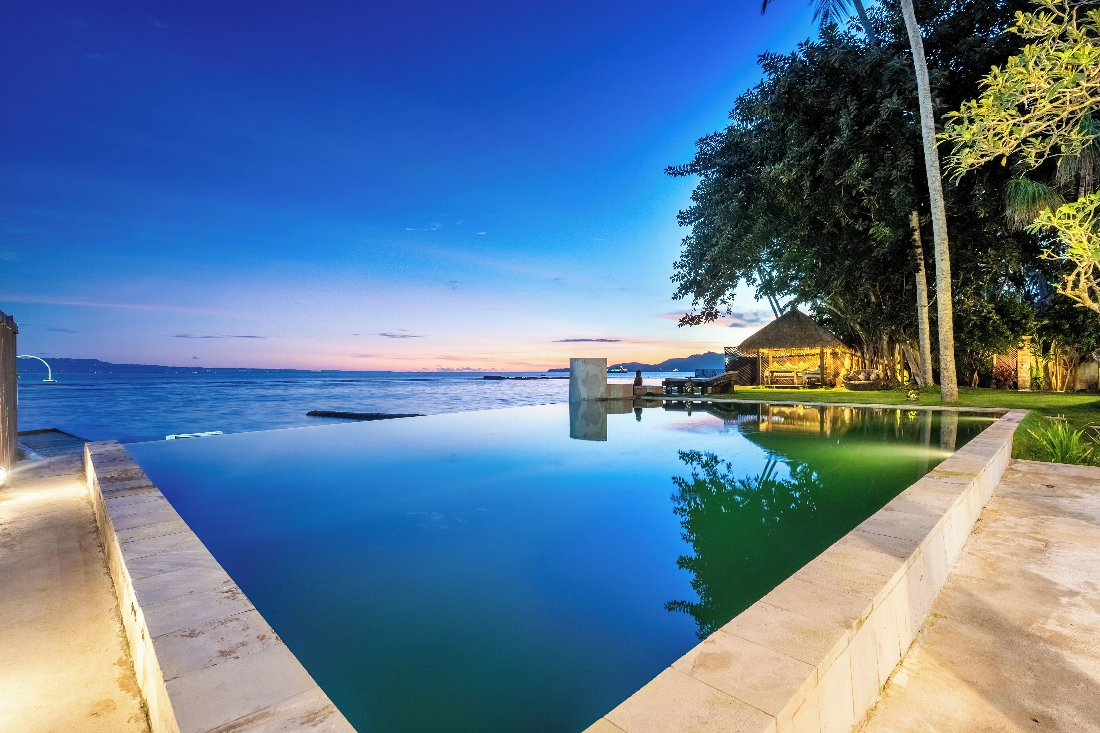 An infinity pool with a view of the ocean at dusk.