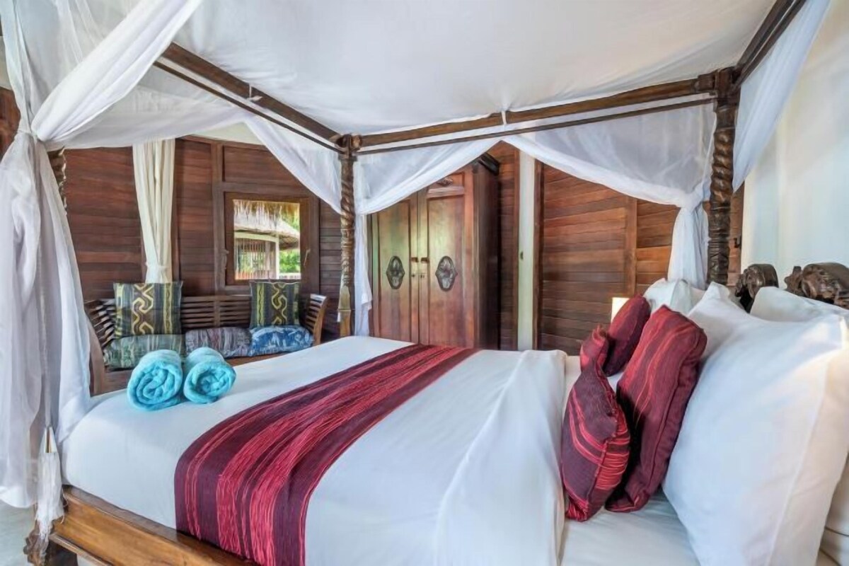 A bed with a canopy, wooden walls, and a view of the outdoors.