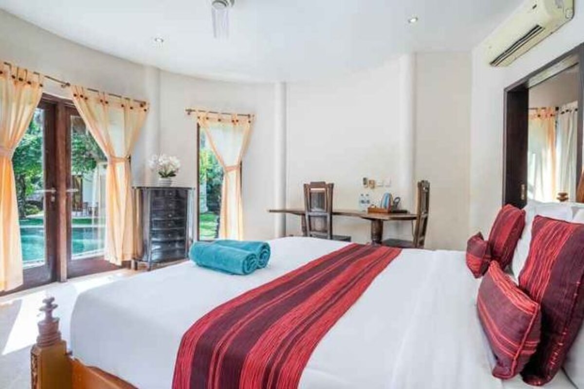 A hotel room with a large bed, a desk, and a view of the outdoors.