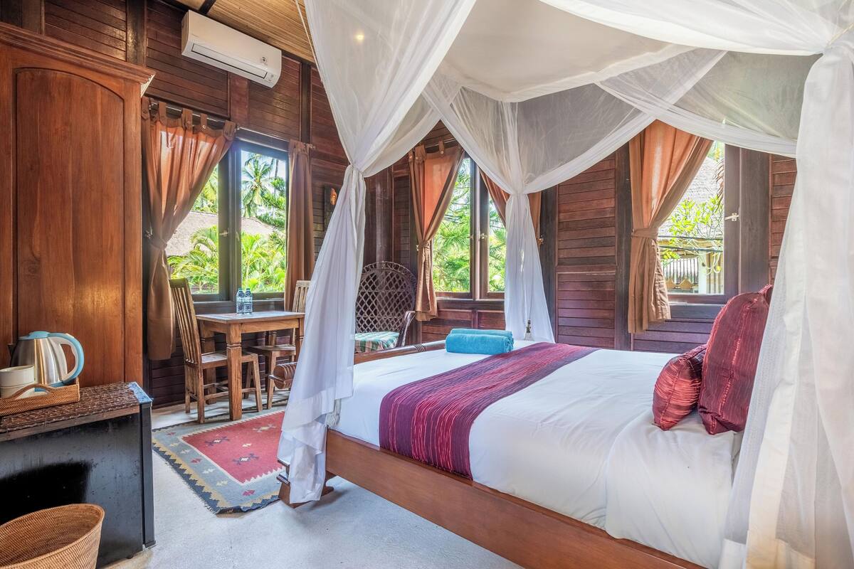A room with a bed, a table, chairs, and a window with curtains.