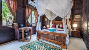 A wooden room with a four-poster bed, a wooden desk, and a chair.