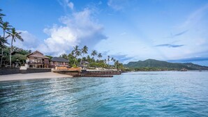 A beachfront property with a large house, a smaller building, and a dock extending into the water. - The Village of Angels (Manggis)