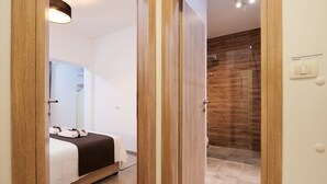 Habitación de hotel con cama, baño con pared de madera y un interruptor de luz en la pared.