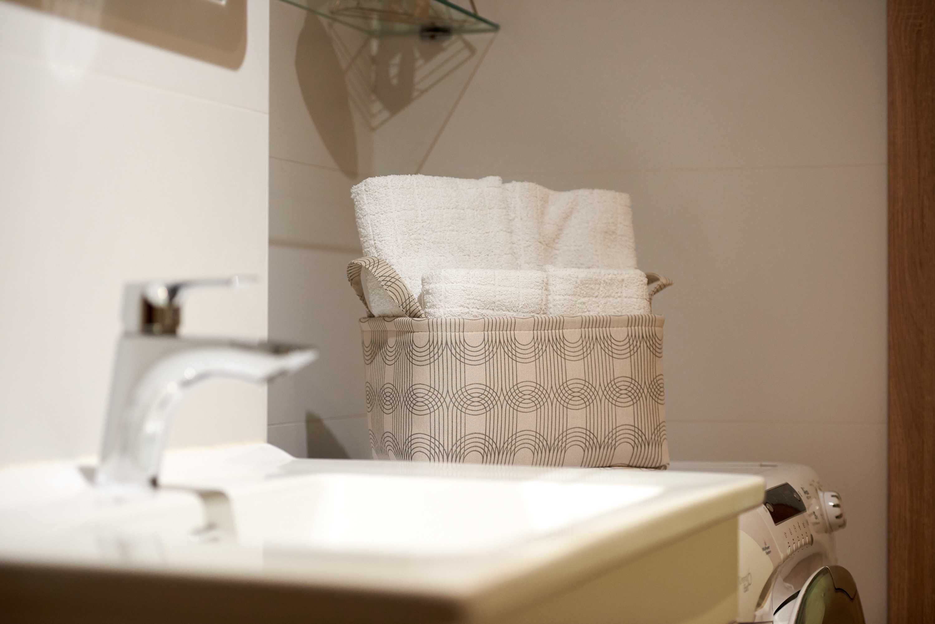 A bathroom with a sink, a towel rack, and a washing machine.