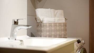 A bathroom with a sink, a towel rack, and a washing machine.