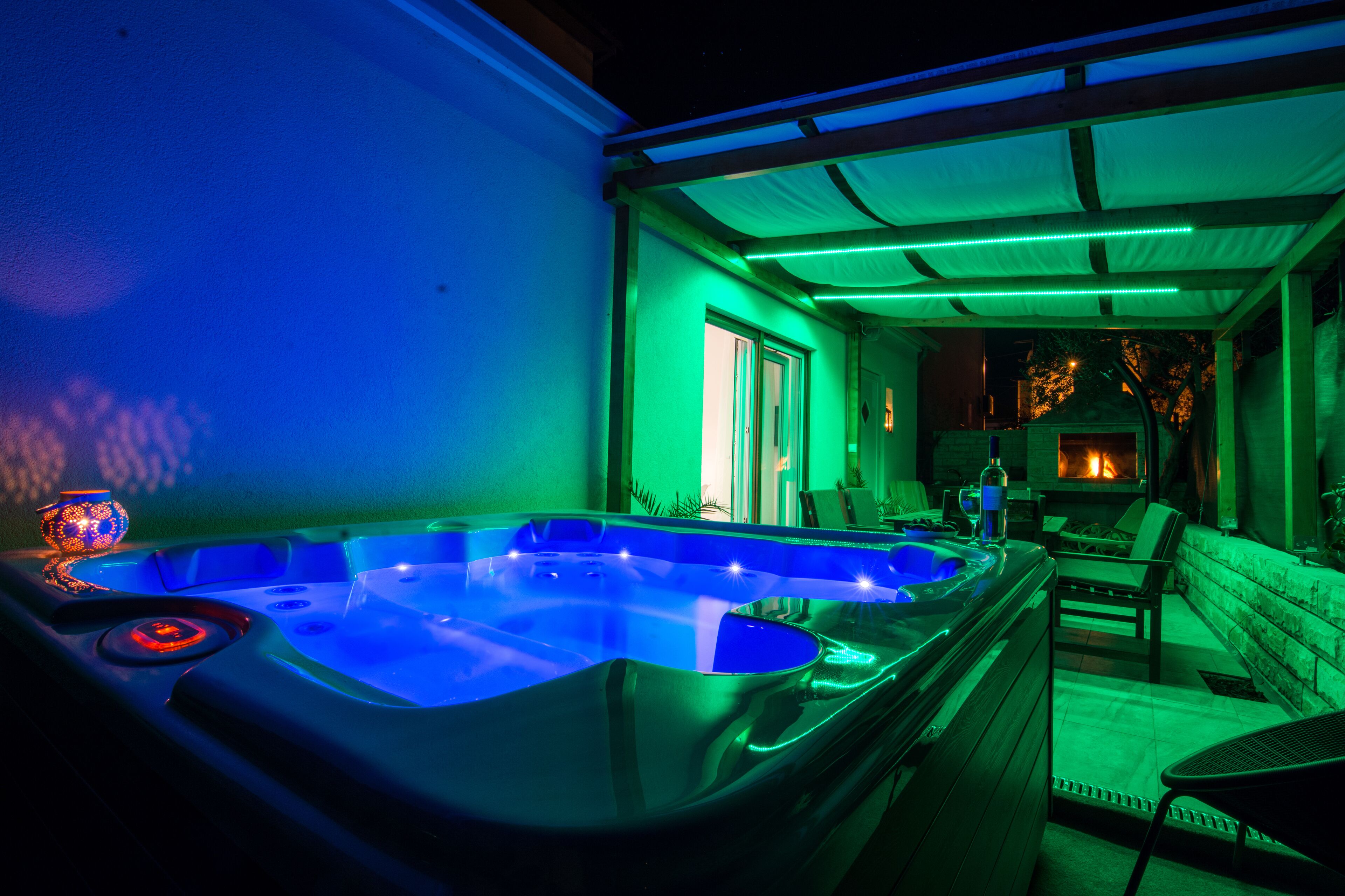 A hot tub with a wooden bench and a fire pit in the background.