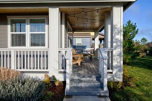 Enjoy outdoor dining or relaxation on the covered porch with a wooden deck and stairs leading to the entrance.
