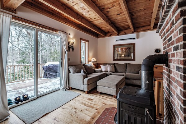 A cozy living room with a fireplace, a sofa set, and a large sliding glass door leading to a deck.