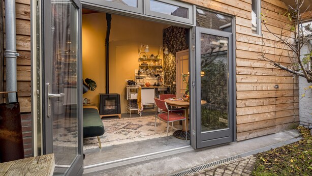 Una casa moderna de madera con amplias puertas correderas de vidrio que dan a un interior luminoso.