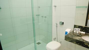 Et badeværelse med et glasbadeafskærmning, et hvidt toilet og en vask med bordplade i granit.