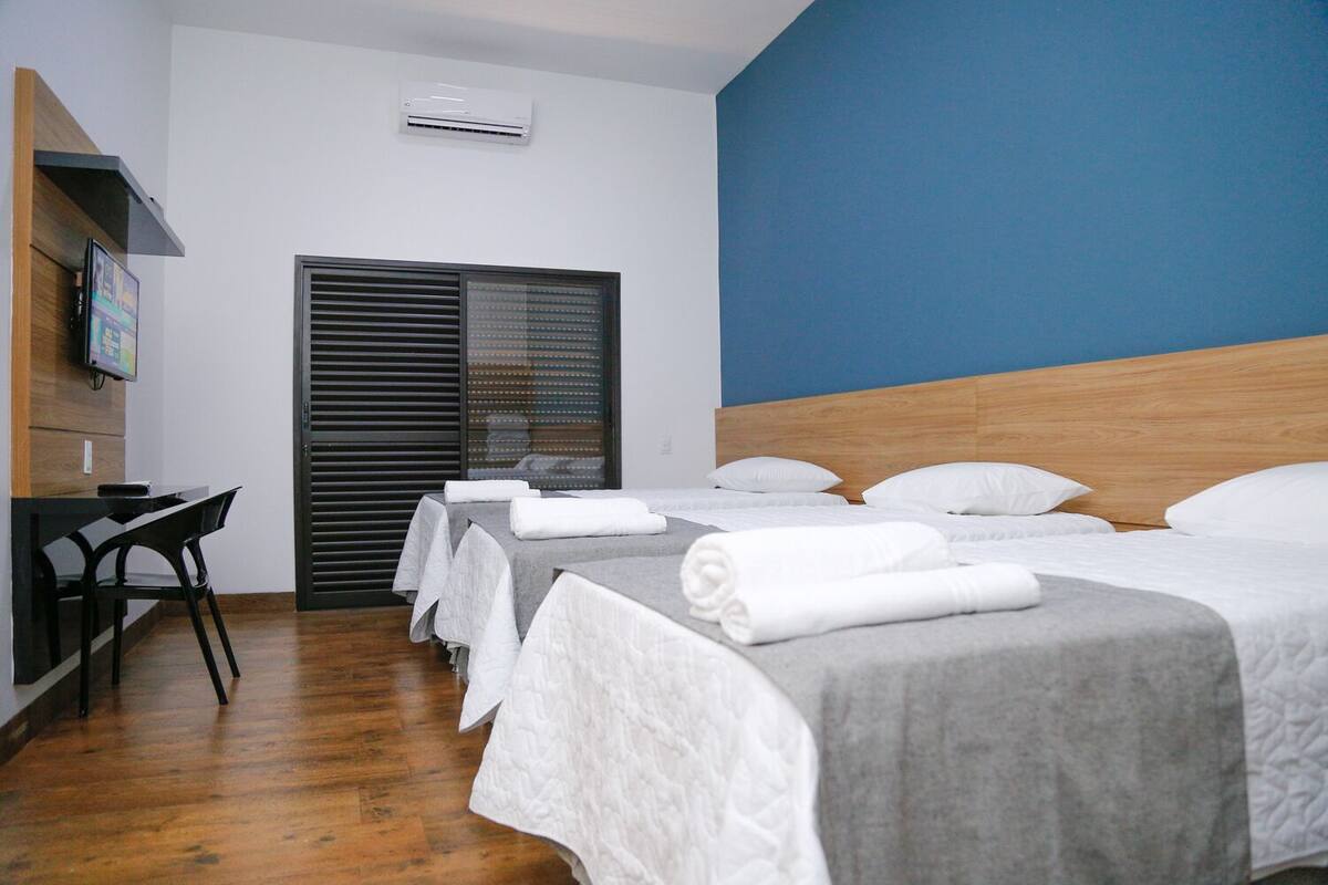 Une chambre d’hôtel avec trois lits, un bureau et une chaise.