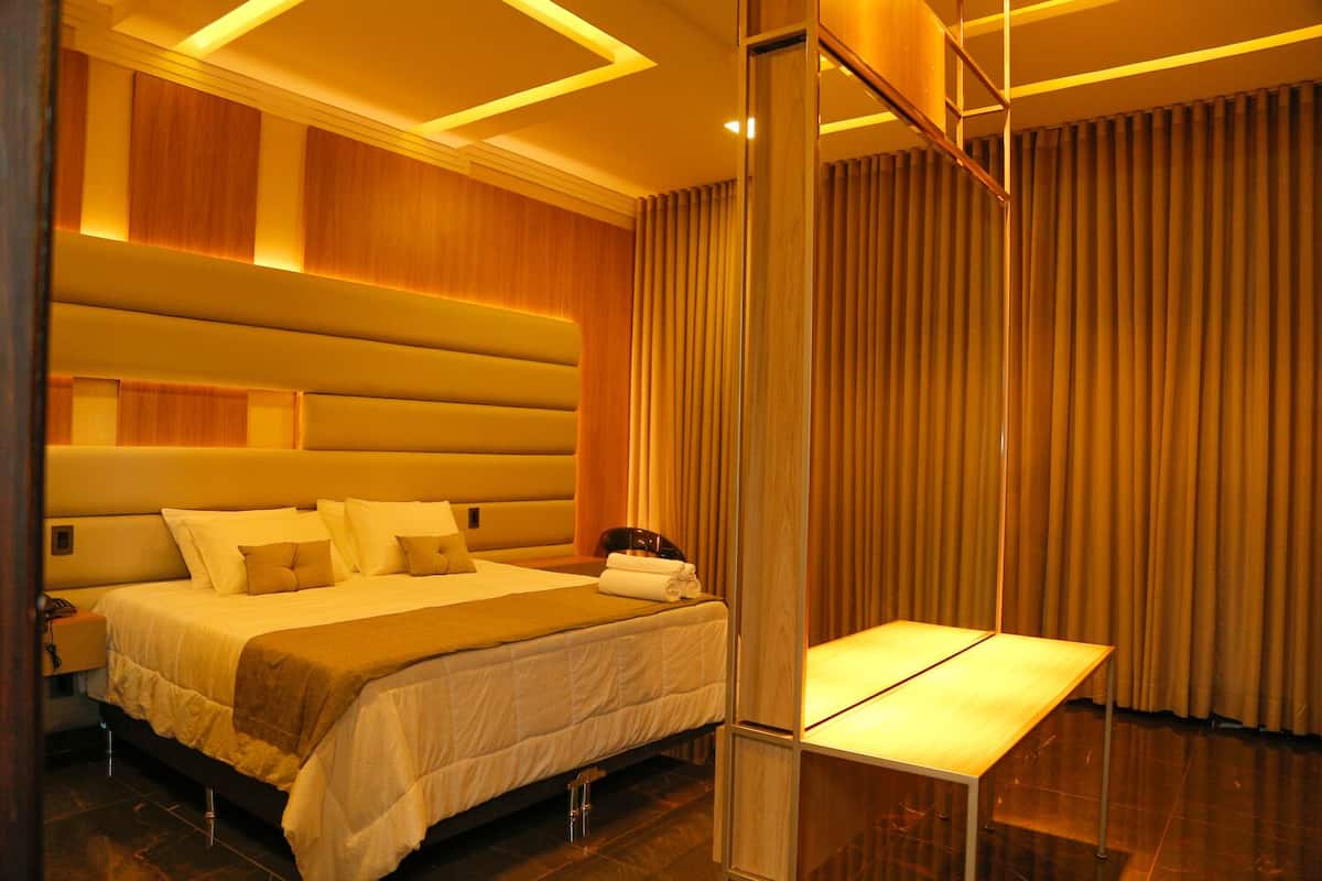 Une chambre d’hôtel moderne dotée d’un grand lit, d’une table de chevet et d’une tête de lit avec éclairage intégré.