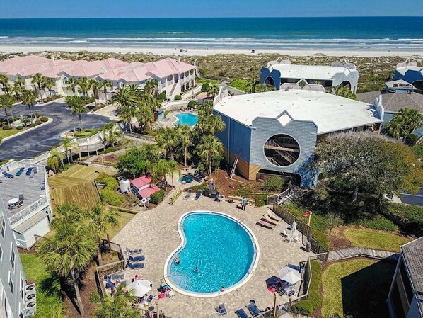 Relax by the resort's large pool surrounded by sun loungers and lush greenery, with the ocean view just steps away.