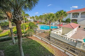 Relax by the resort's pool surrounded by lush greenery and palm trees, with lounge chairs available for a comfortable stay.
