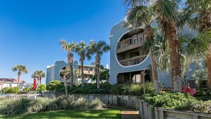A modern hotel with a curved facade, outdoor pool, and palm trees. - Hibiscus Resort Pool View Condo (St. Augustine)