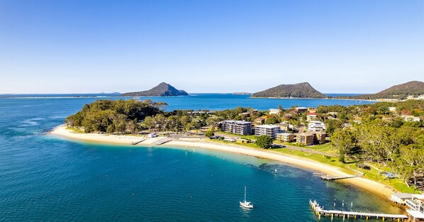 A coastal resort with beachfront properties, a marina, and a mountainous backdrop.
