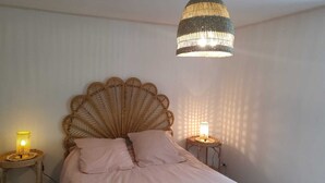 Een slaapkamer met een groot bed, twee bedlampen en een hangende lamp.