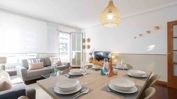Un salon moderne comprenant un coin repas, un canapé, un téléviseur et une grande fenêtre.