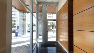 Un hall d’hôtel moderne avec des portes en verre, un mur en bois et un sol en marbre.
