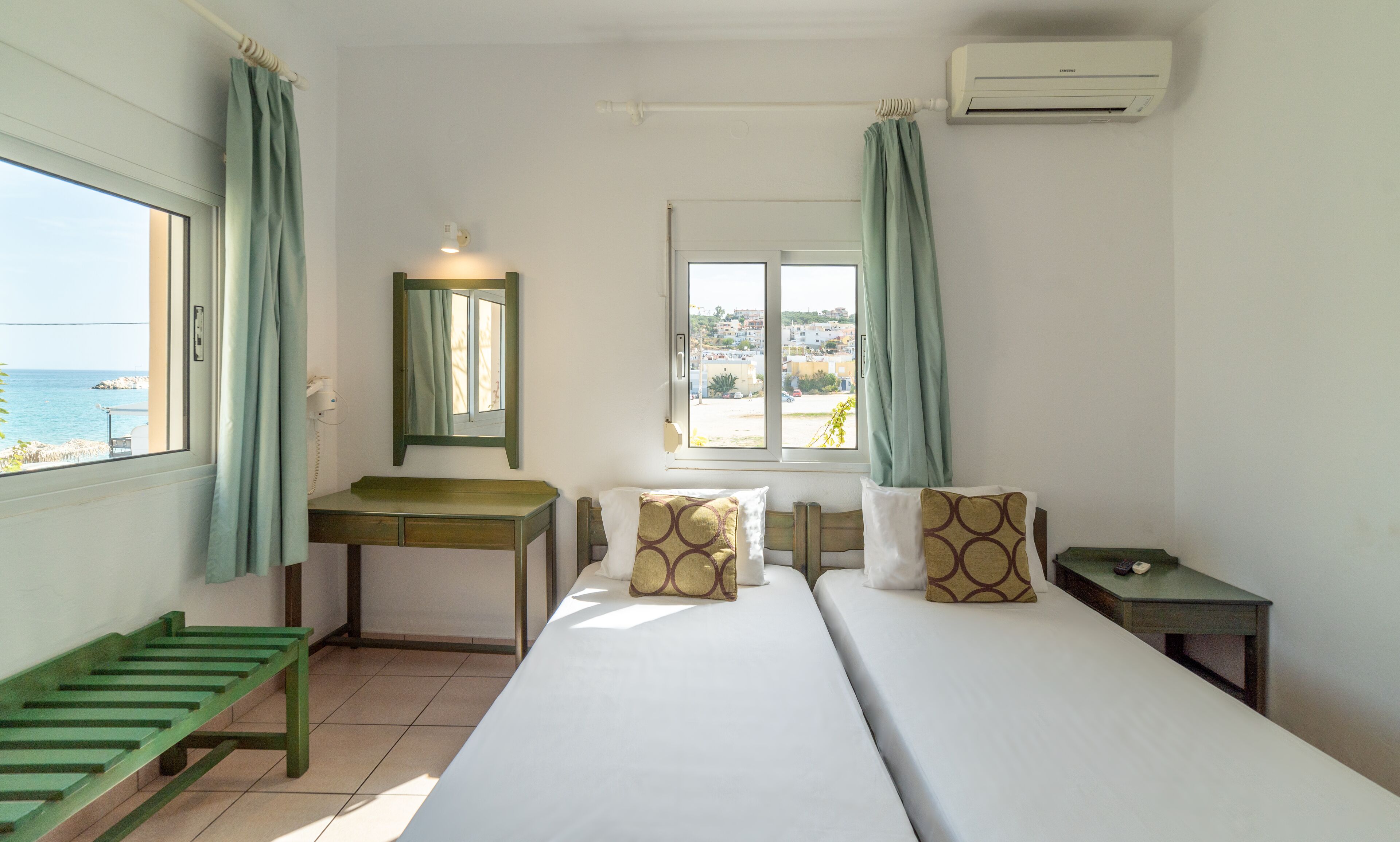 Une chambre à coucher comprenant un lit, un bureau, une chaise, une fenêtre donnant sur la mer et un appareil de climatisation.