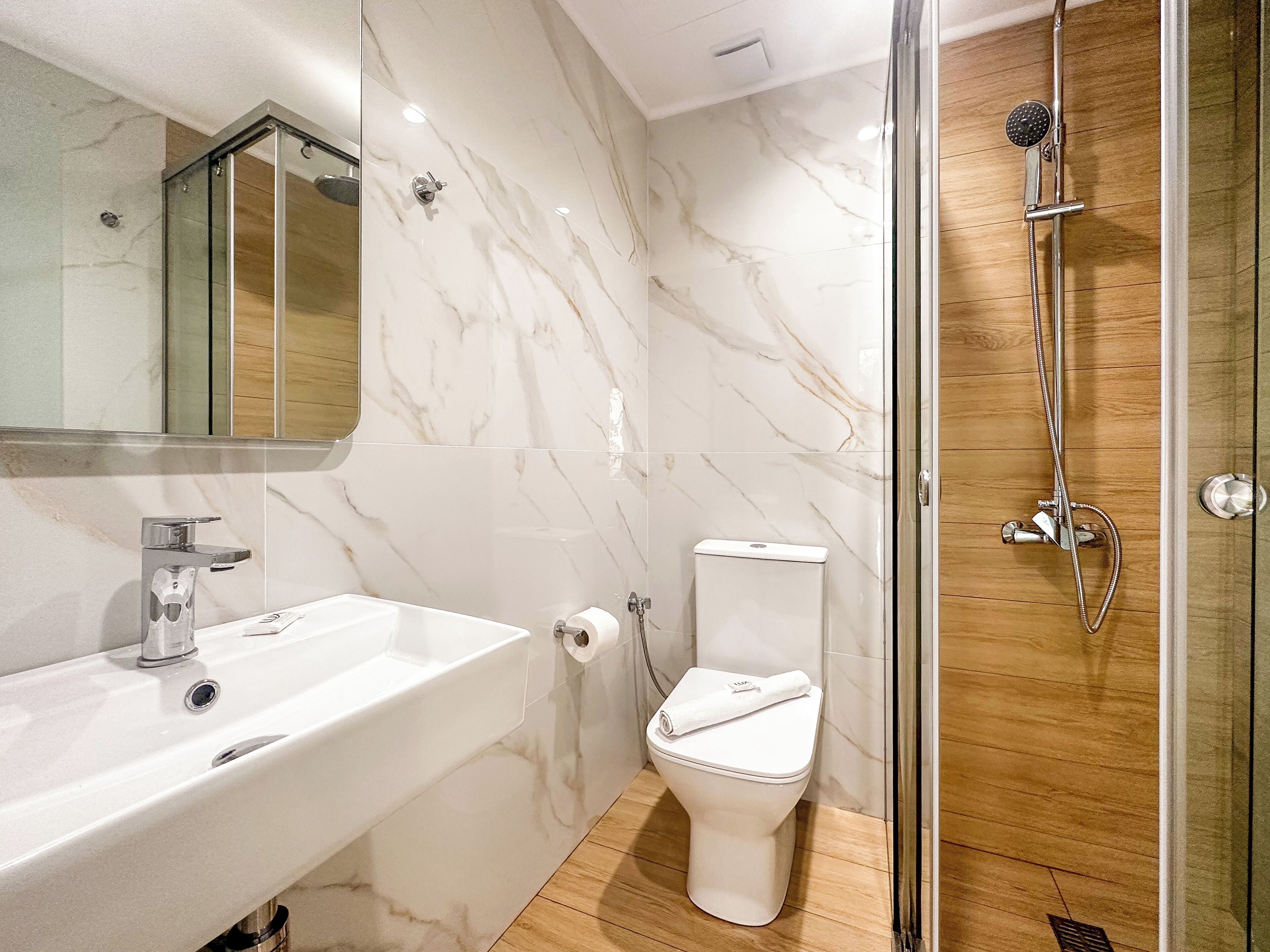 A modern bathroom with a marble sink, toilet, and shower.