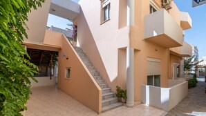 Un bâtiment moderne avec un escalier menant à un étage supérieur, un espace extérieur couvert et un panneau indiquant qu’il faut tourner à droite.
