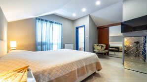 Ein Hotelzimmer mit einem großen Bett, einem Sessel, einem Schreibtisch und einem Fernseher.