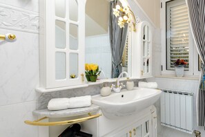A bathroom with a white sink, gold fixtures, a mirror with a striped curtain, and a radiator. - Villa Piano (Zupa dubrovacka)