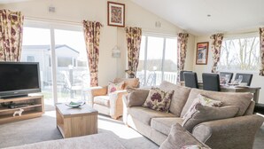 A spacious living room with a flat-screen TV, a wooden coffee table, and a sofa set. - Superb Detached Lodge Located on Skipsea Sands (Driffield)
