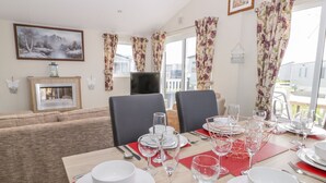 A dining area with a wooden table set for four, surrounded by chairs. - Superb Detached Lodge Located on Skipsea Sands (Driffield)