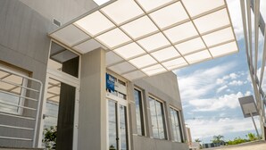 Un edificio moderno con una amplia entrada de vidrio, un letrero que dice 'Ibis Boutique Hotel', y un cielo despejado.