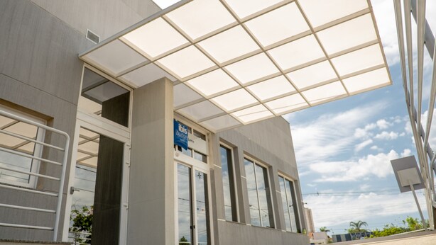 A modern building with a large glass entrance, a sign for 'Ibis Boutique Hotel', and a clear sky. - ibis budget Leme (Leme)