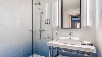 Un baño moderno con cabina de ducha de vidrio, un lavabo blanco y un espejo sobre él.